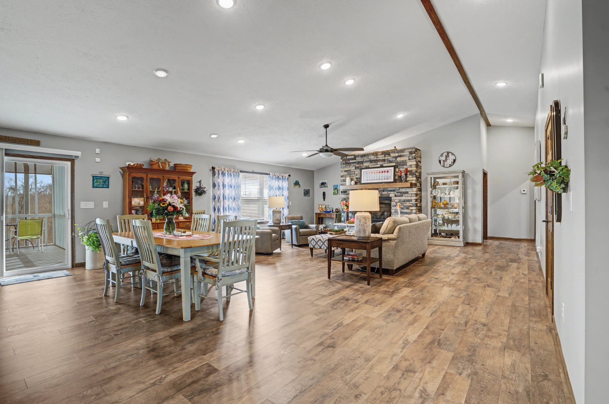 Open-concept living and dining room with stone fireplace, vaulted ceiling, and hardwood floors at 109 Clare Kennedy Drive in Marietta, Ohio by Horizon Heights Productions.